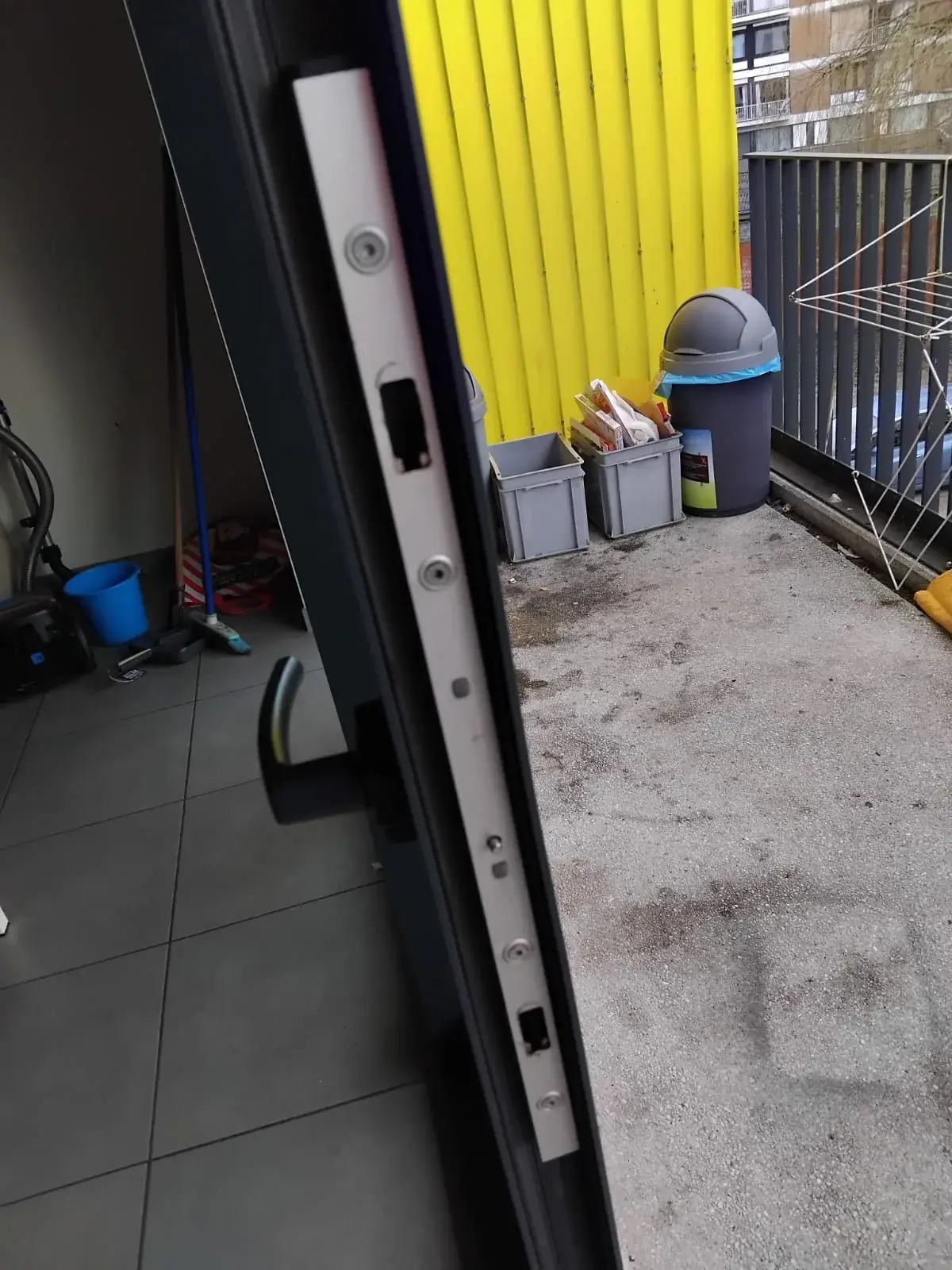 Crémone d'une porte-fenêtre en aluminium anthracite donnant sur un balcon