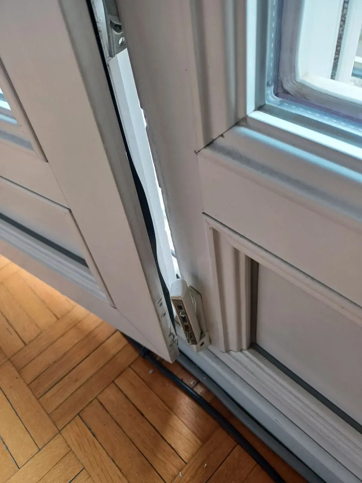 Porte-fenêtre ouverte et ferrure basse contrôlée dans une maison d'Auderghem